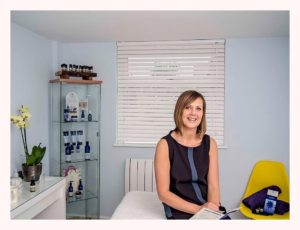 Sarah Bond sitting on the end of her treatment couch in her therapy room in Rustington